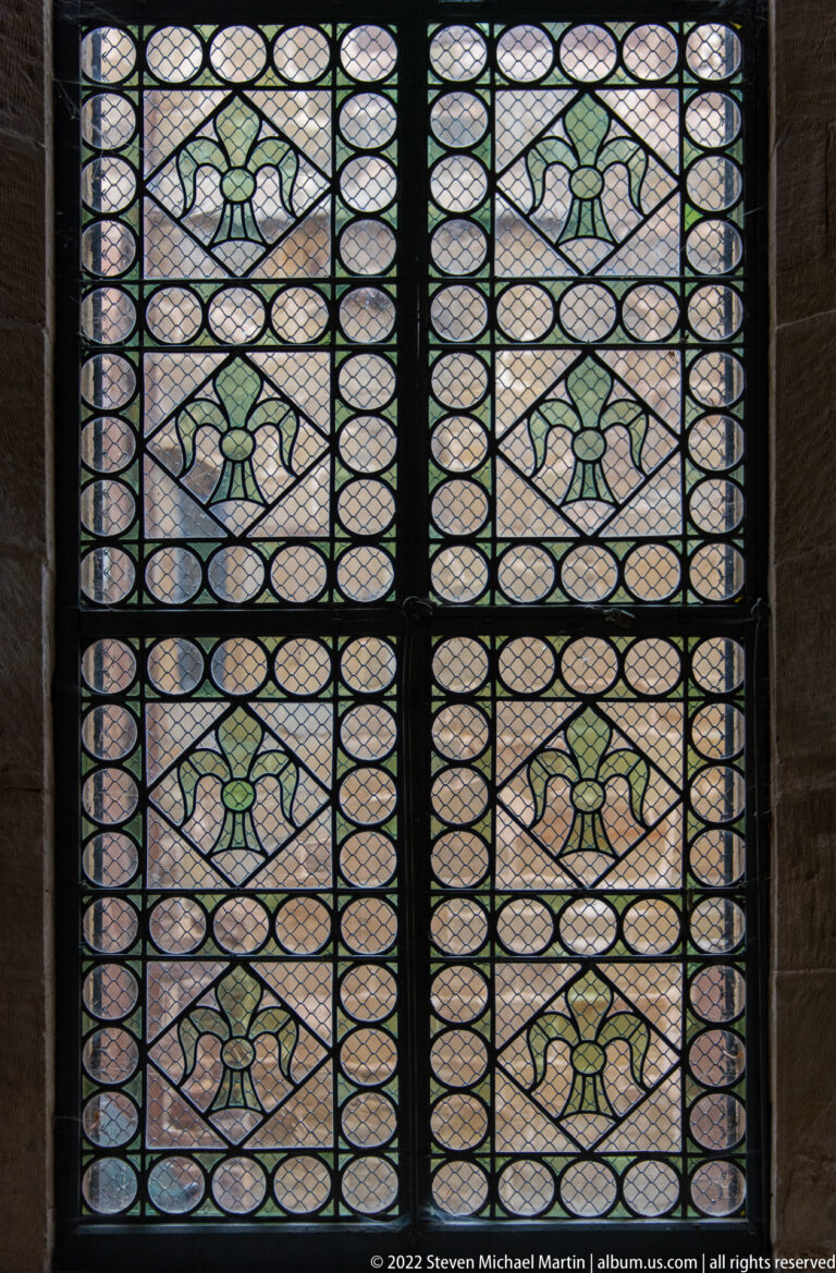 Leaded-glass window with repeating green decorative motifs set in oval and circular patterned panes.