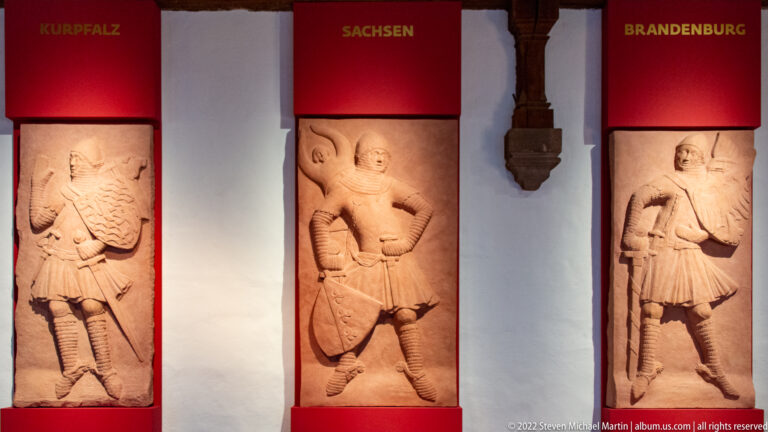 Two carved armed figures beneath red banners labeled Sachsen and Brandenburg.