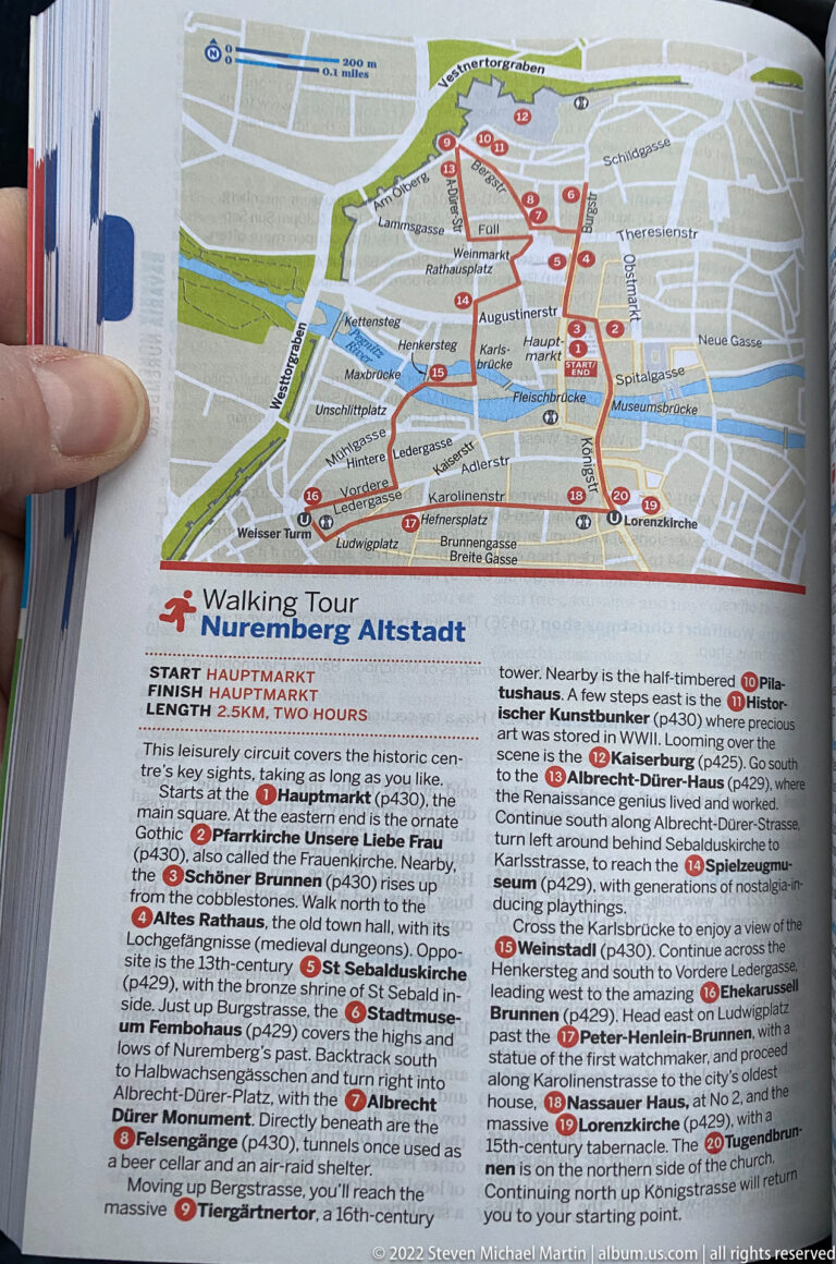 Printed walking-tour map of Nuremberg Old Town with a red route, numbered stops, and explanatory text.