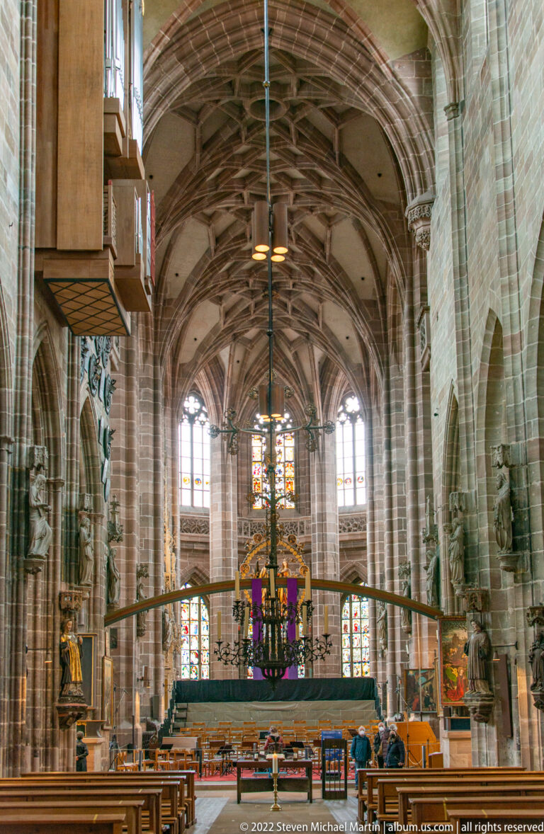 View into the St. Lorenz choir with ribbed vaults, clustered columns, stained glass, and sanctuary furnishings.