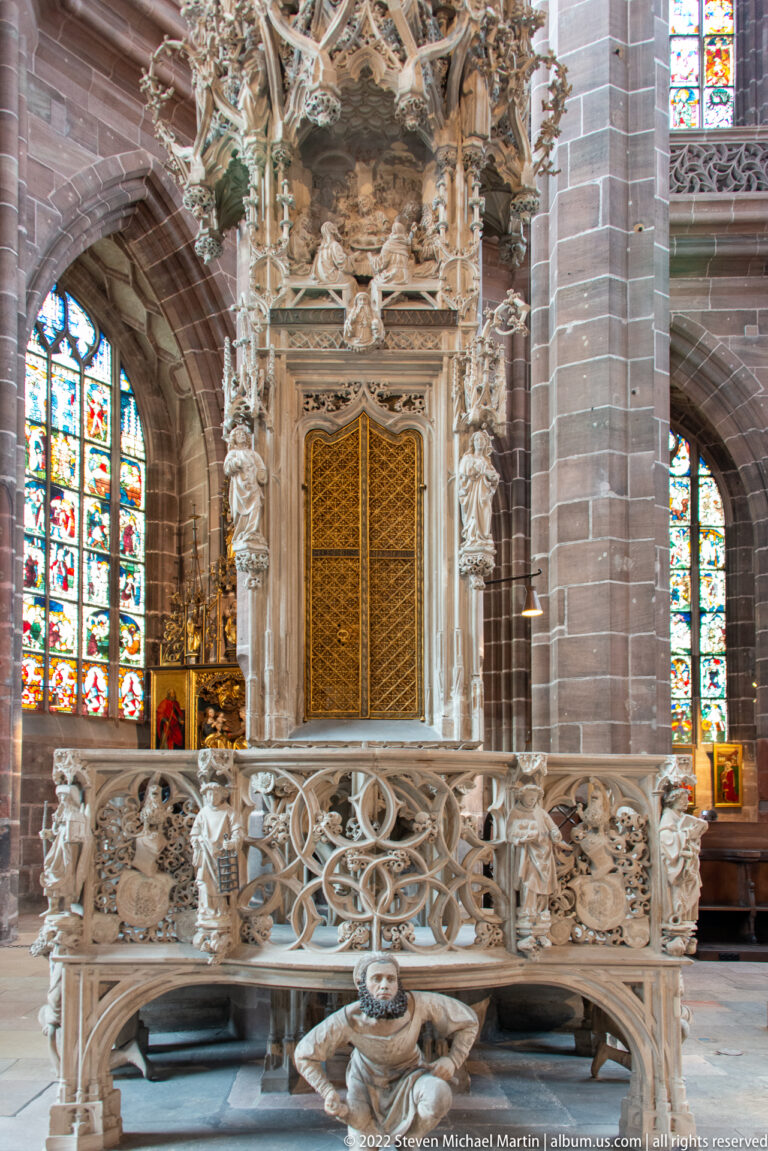 Elaborate late-Gothic stone Sacrament House with tracery, pinnacles, figures, and a central tabernacle beneath stained glass.
