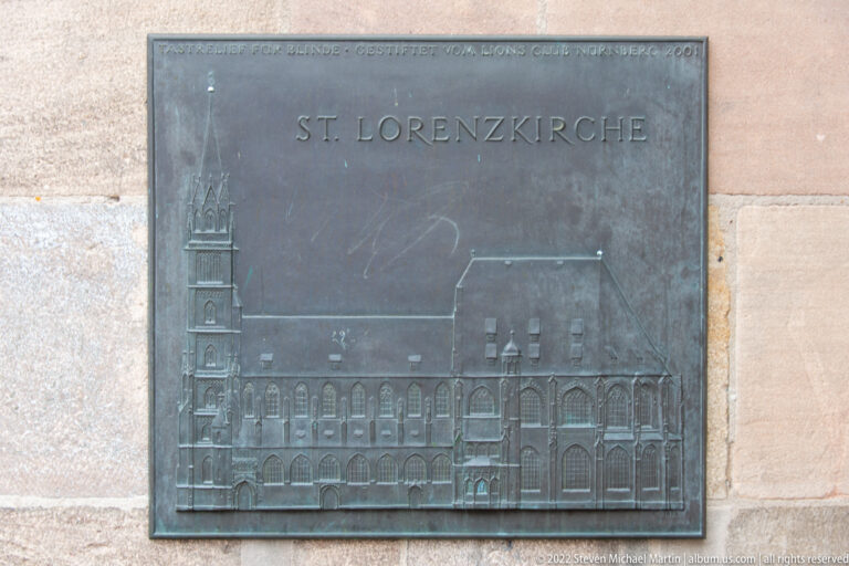 Bronze plaque labeled ST. LORENZKIRCHE with a raised side elevation of the church.