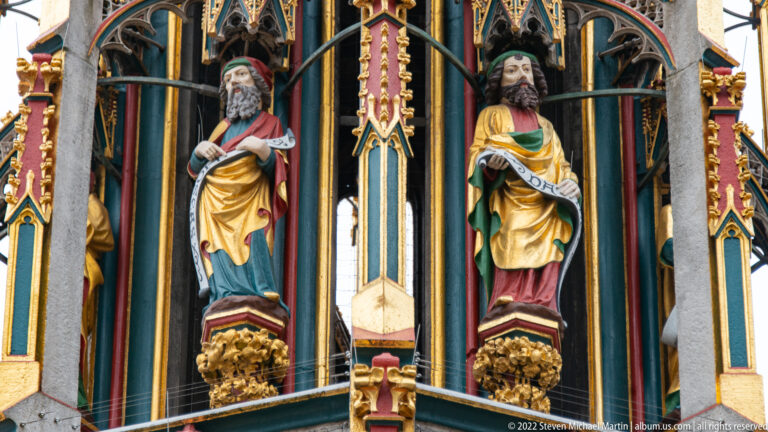Two polychrome figures standing in narrow Gothic niches on the richly decorated Schöner Brunnen.