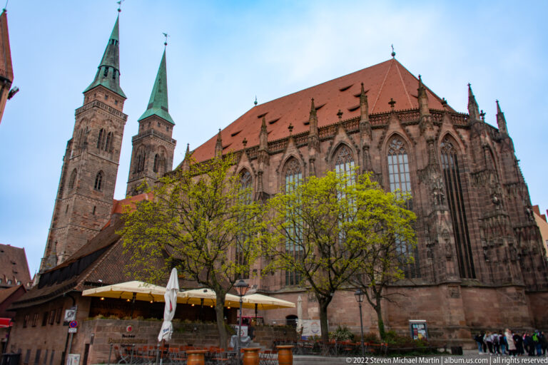 St. Sebald Church with twin towers, tall Gothic choir, buttresses, traceried windows, and red roof.