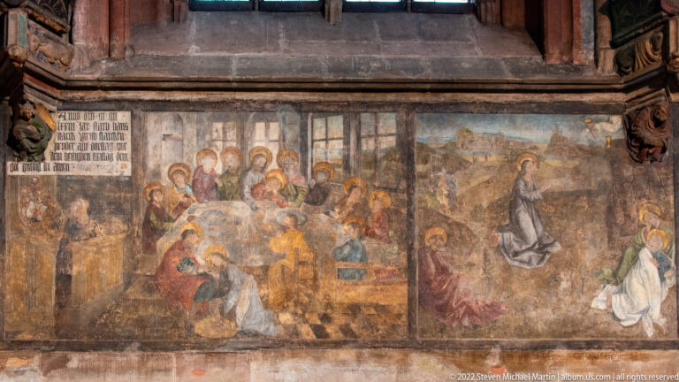 Faded religious wall painting with groups of haloed figures, a larger sacred figure, and a small inscription block.