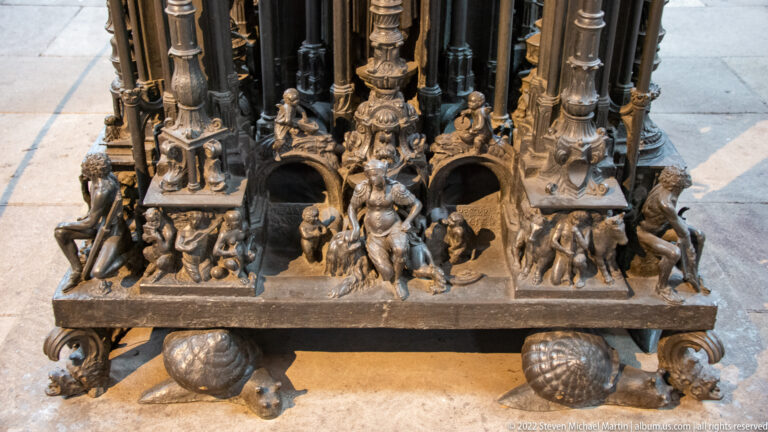Close view of the Tomb of Saint Sebald base with small figures, creatures, arches, and rounded supports.