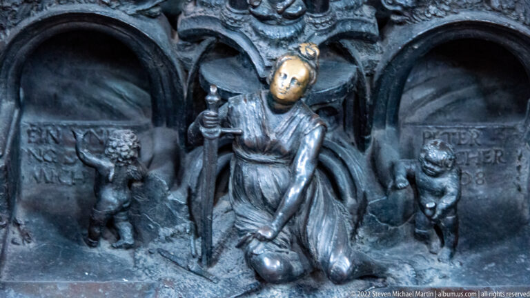 Kneeling bronze figure of Peter Vischer with tools and apron beside identifying inscriptions on Saint Sebald’s tomb.