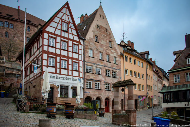 Red-and-white half-timbered building signed Zum Albrecht Dürer Haus beside a tall pale stone gabled house.