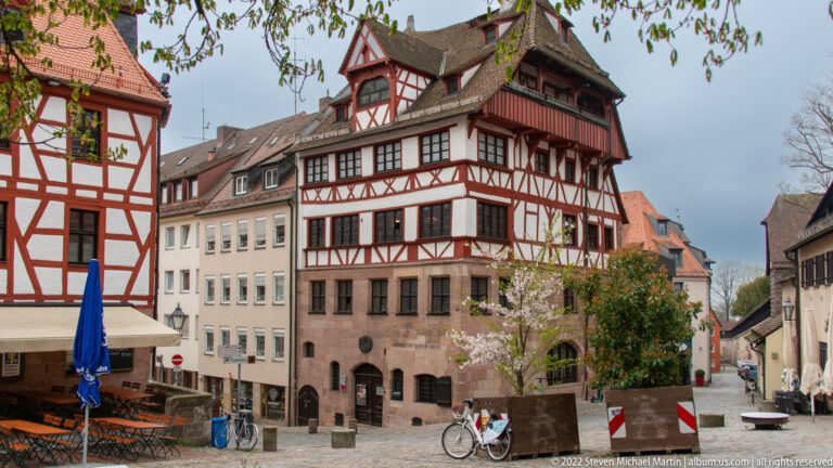 Historic multi-story house with masonry base, projecting half-timbered upper floors, and deep roof eaves.