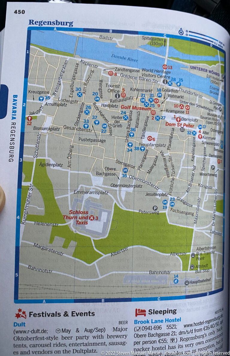 Folded printed map of central Regensburg showing streets, landmarks, visitor symbols, green areas, and the Danube.