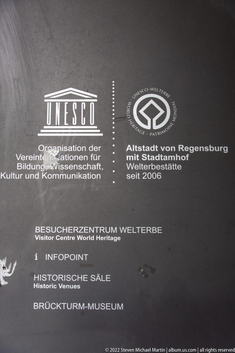 Dark information panel with UNESCO and World Heritage logos and directions for Regensburg visitor attractions.