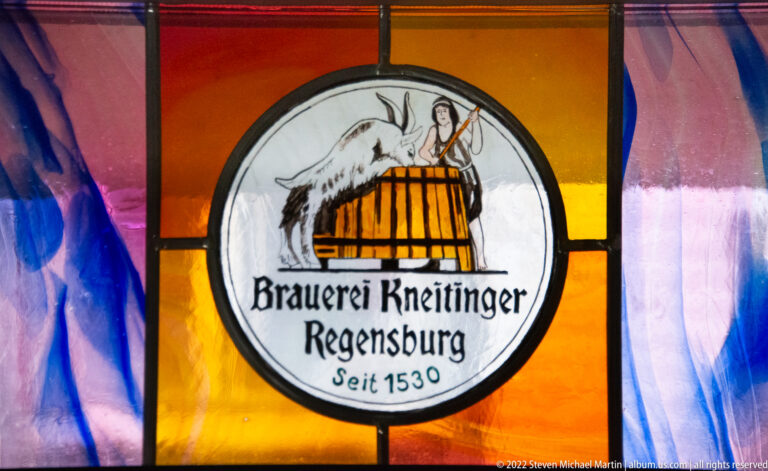 Stained-glass Brauerei Kneitinger emblem showing a goat and barrel with Regensburg and Seit 1530 lettering.