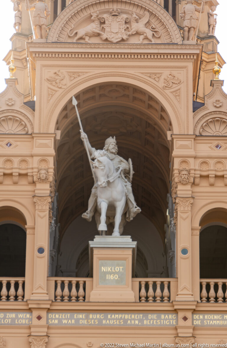 Mounted statue of Niklot in an arched niche above a plaque reading “NIKLOT 1160.”