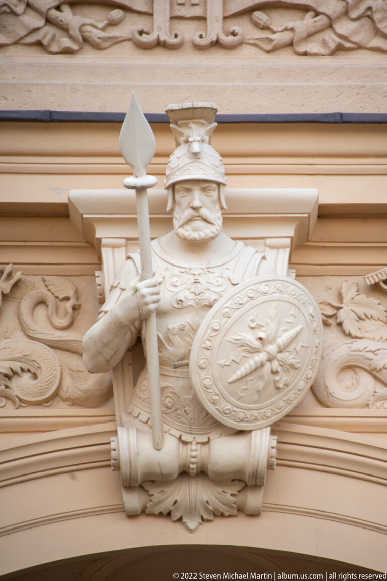 Carved armored warrior holding a staff and round heraldic shield on Schwerin Castle.