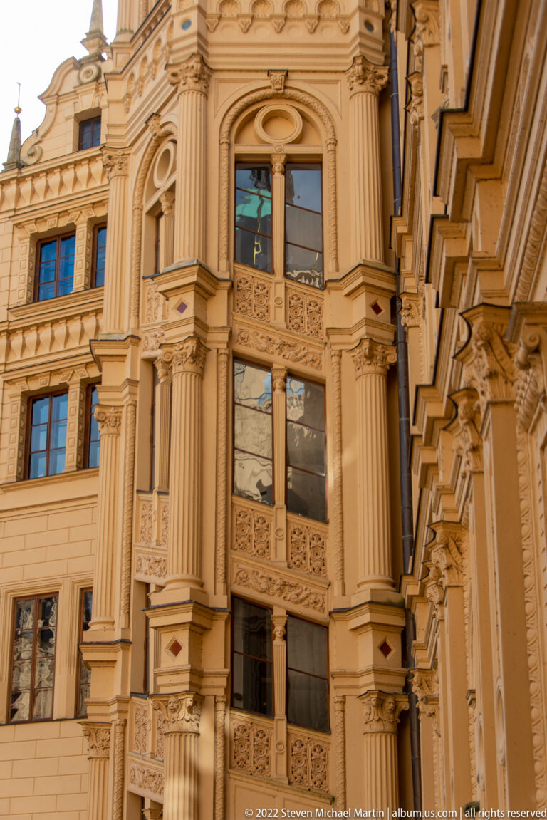 Close view of tall windows, fluted pilasters, carved panels, and moldings on Schwerin Castle.