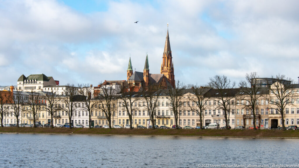 Schwerin Cathedral spire above pale waterfront buildings across Pfaffenteich.
