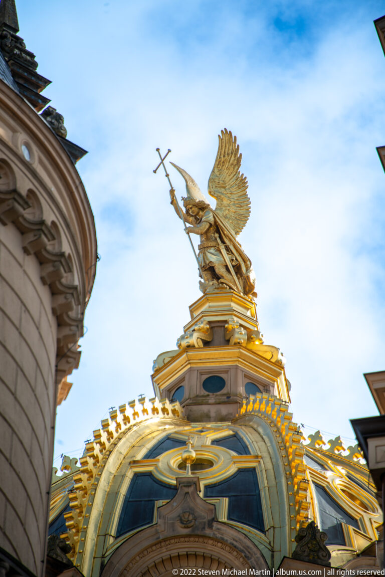 Gilded winged Saint Michael with raised weapon crowning the ornate roofline of Schwerin Castle.