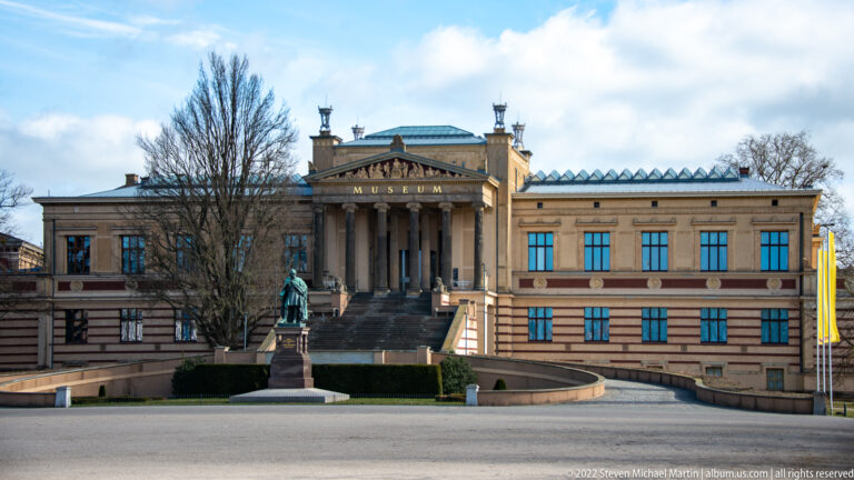 Staatliches Museum Schwerin with broad staircase, columned portico, MUSEUM inscription, and monument in front.