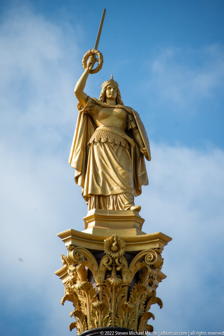 Gilded female figure raising a sword atop an ornate pinnacle of Schwerin Castle.