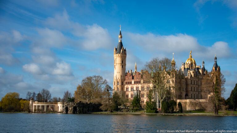 Schwerin Castle on its island, with tall tower and gilded dome beyond the lake.