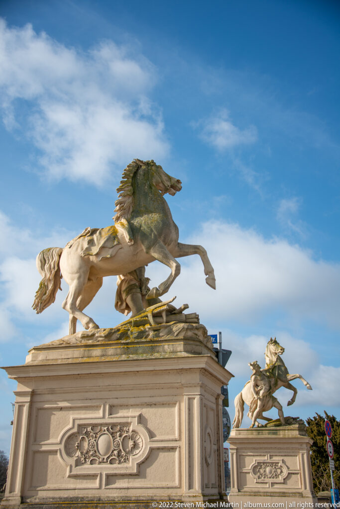 Two pale stone sculptures of rearing horses on balustrades near Schwerin Castle.