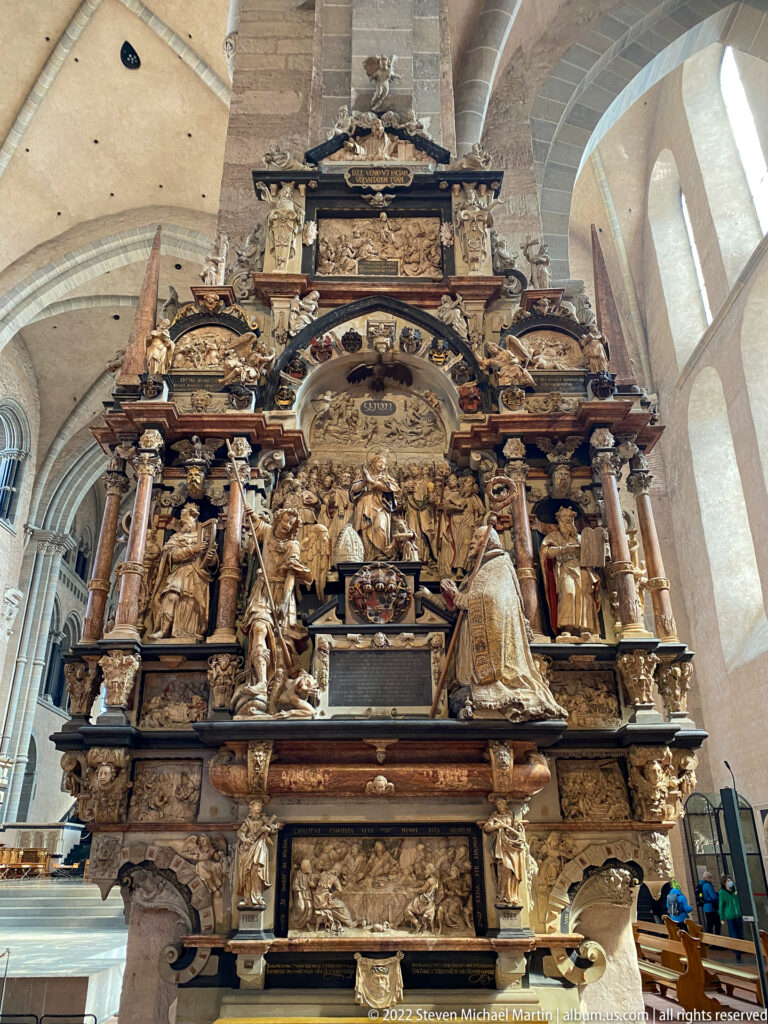 Large Baroque church monument with columns, many sculpted figures, relief panels, inscriptions, and a central roundel.