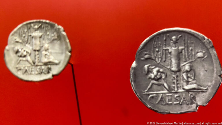 Two ancient silver coins showing a standing figure with smaller figures below and the inscription CAESAR.
