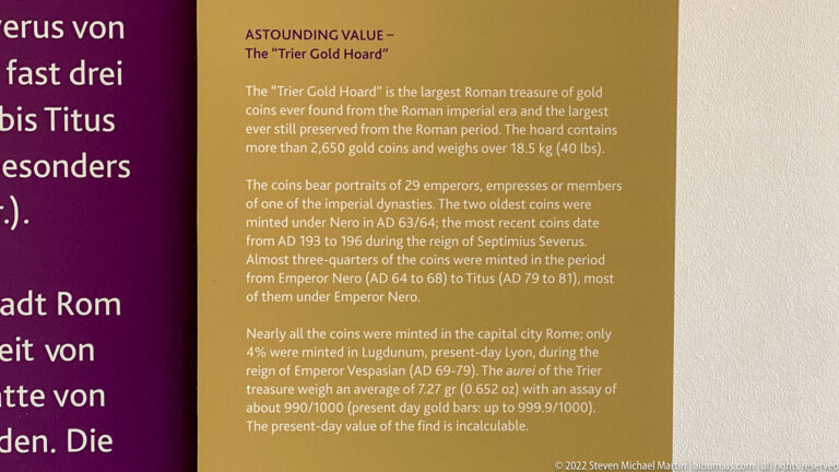 English museum panel titled for the Trier Gold Hoard with text describing Roman gold coins, emperors, weight, and minting.
