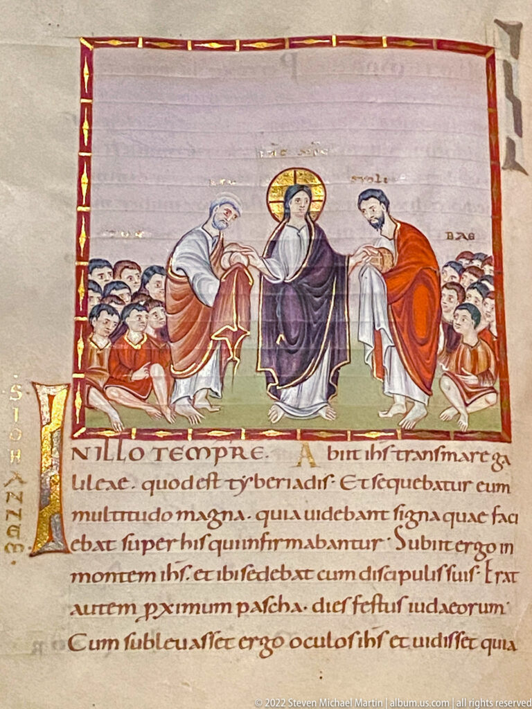Illuminated manuscript with haloed Christ at center, two standing figures, crowd, decorated initial, and Latin text below.