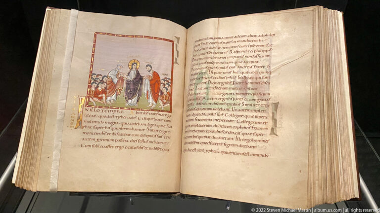 Large open parchment manuscript with Christ-centered illuminated miniature on the left page and dense Latin text on the right.