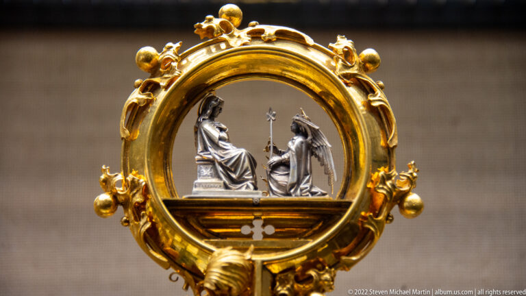 Ornate gilded oval frame containing a miniature silver-toned scene with a seated figure and a kneeling figure.