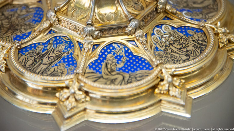 Gilded ecclesiastical metalwork with blue enamel medallions showing sacred figures and dense ornamental borders.