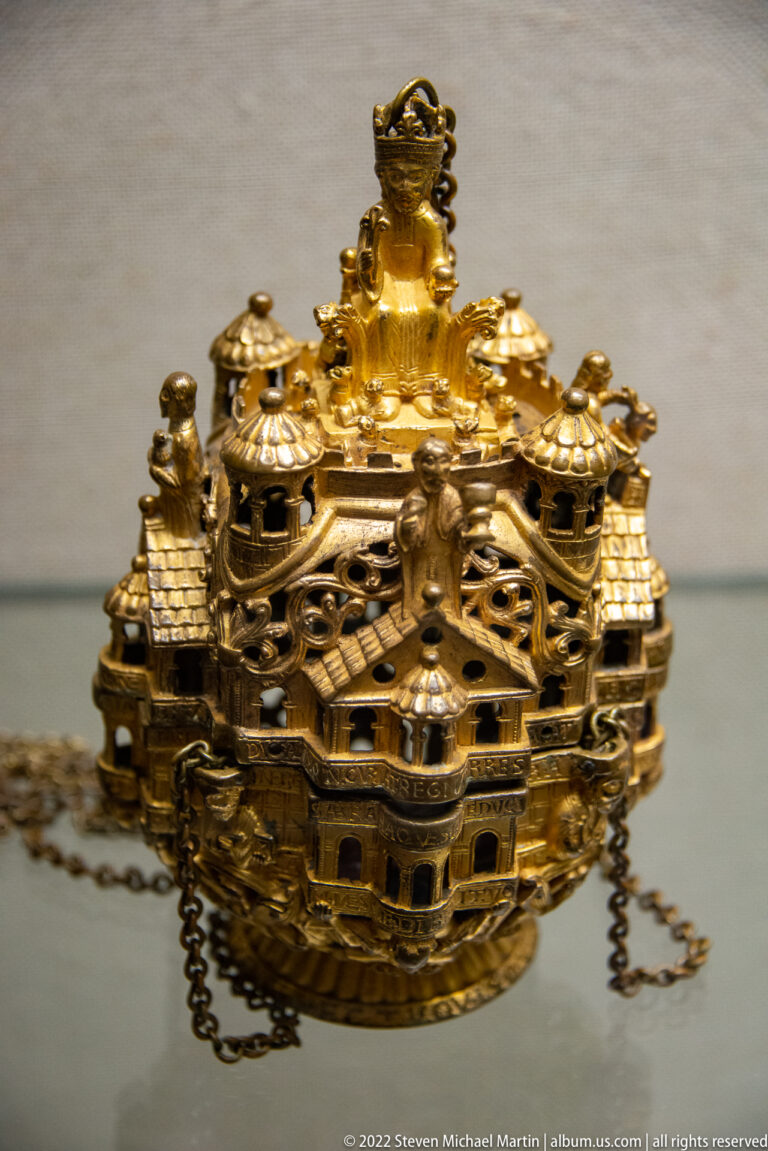 Gilded architectural-form censer with miniature towers, openwork walls, small roofs, and a metal chain.