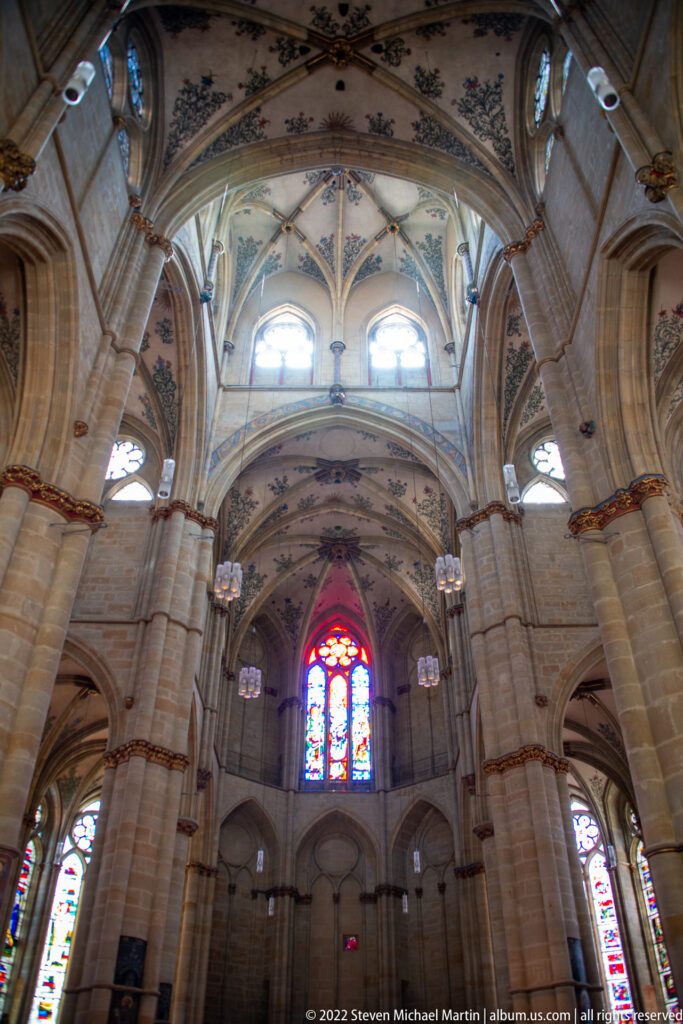 Upward view of Gothic ribbed vaults, pointed arches, clustered columns, and high windows inside a Trier church.