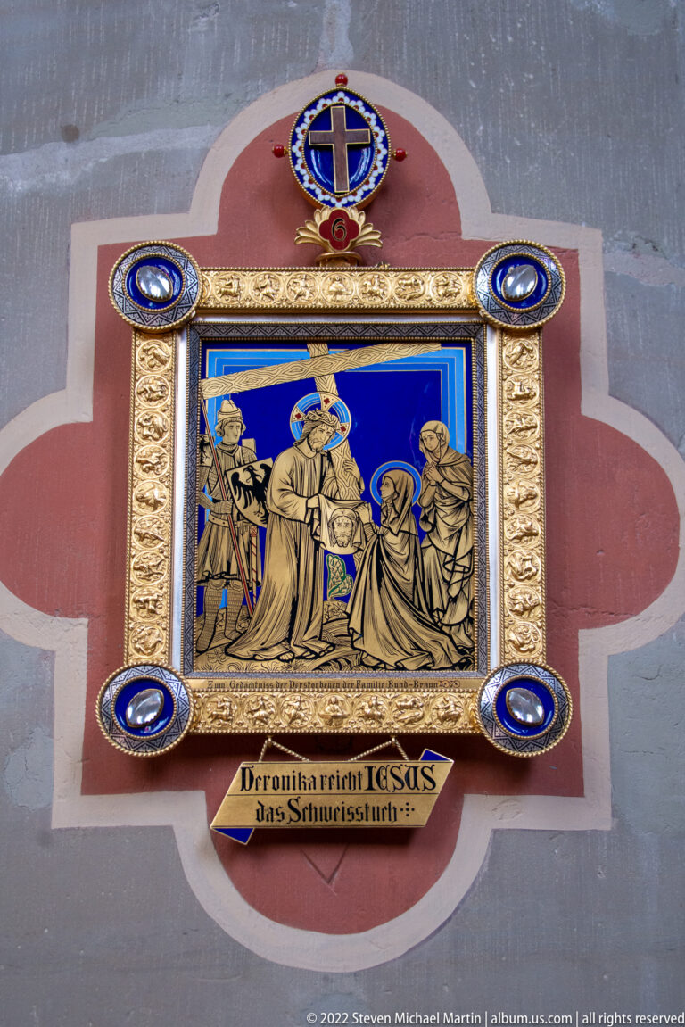 Framed Passion scene on a blue ground with gold ornament, cross emblems, and a German inscription including JESUS.