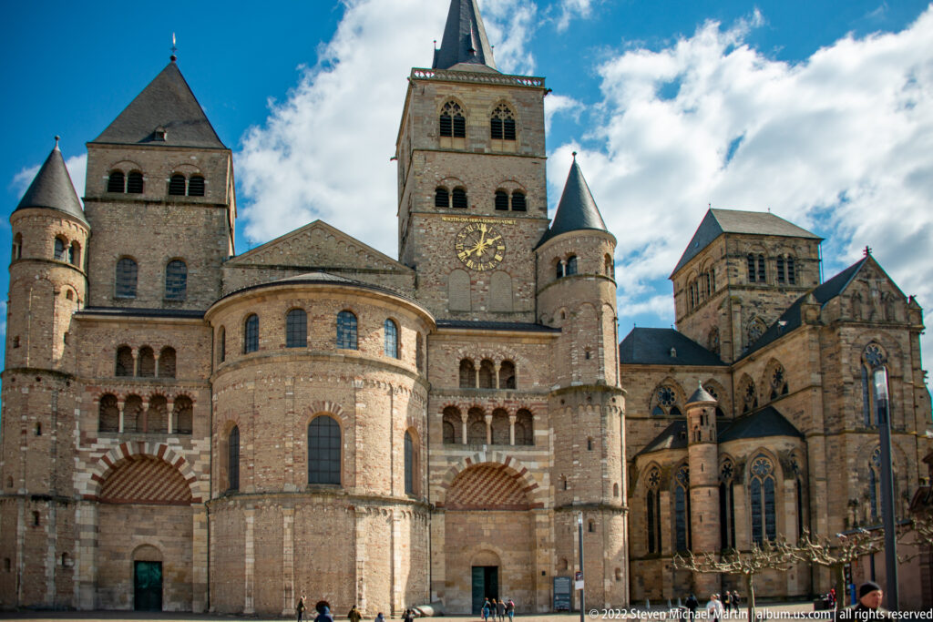 Wide view of Trier Cathedral showing central towers, rounded apses, flanking turrets, and Gothic additions.