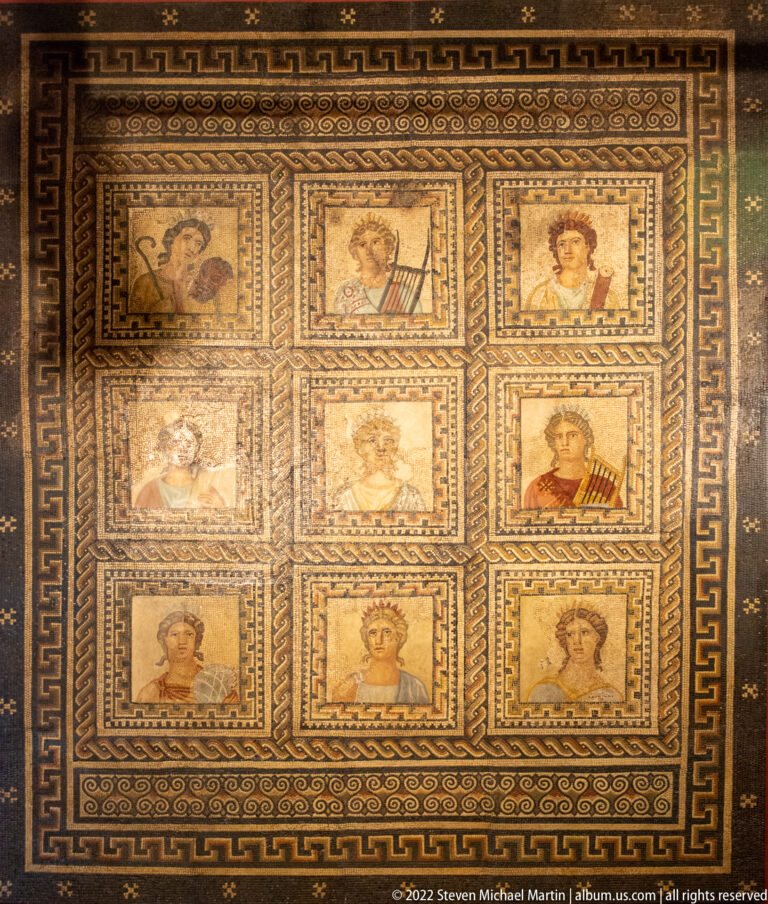 Roman mosaic divided into nine square panels with portrait busts, surrounded by geometric borders.