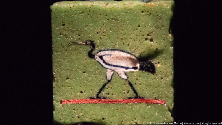 Small Roman mosaic of a long-legged bird with curved bill on a green background and narrow red ground line.