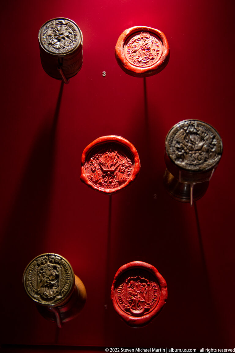 Several circular red and brown wax seals on slender mounts, each bearing impressed heraldic or figural designs.