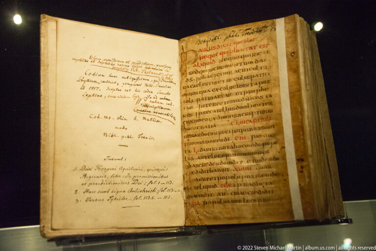 Open parchment manuscript with dense Latin script, red rubrication, and extensive handwritten annotations on the facing page.