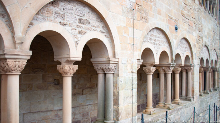 Row of round stone arches supported by slender columns with carved capitals along a Wartburg arcade.