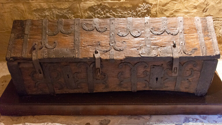 Large wooden chest reinforced with broad iron straps, hinges, and decorative metal fittings.