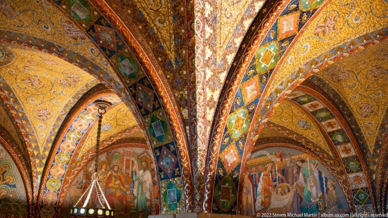 Decorated vaults with gold grounds, colorful geometric patterns, and historical figural scenes between the arches.