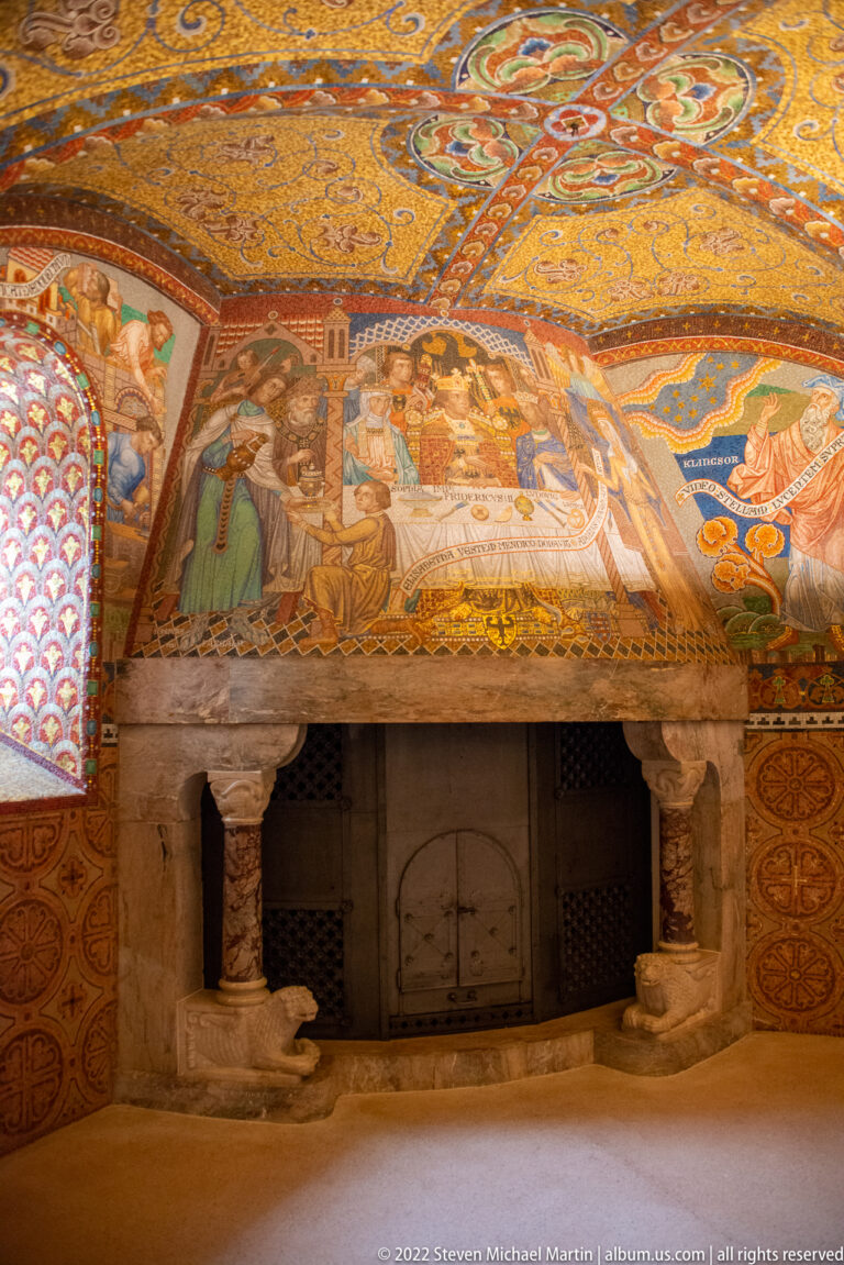 Stone fireplace beneath a painted historical scene in a richly decorated Wartburg interior.