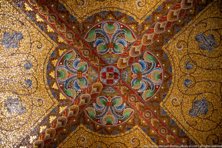 Close view of a gold-ground vault with intersecting decorated ribs and a multicolored central rosette.