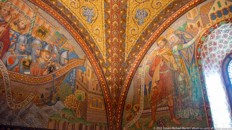 Two colorful historical murals with armored and courtly figures beneath a richly patterned vaulted ceiling.