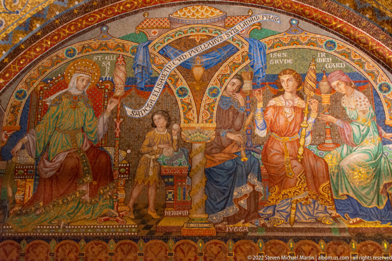 Colorful mural of seated and standing medieval court figures with vessels, banners, and inscription ribbons.