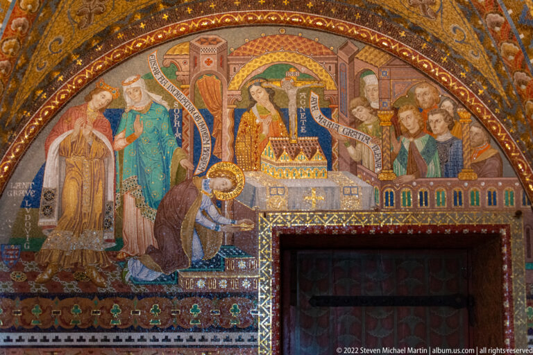 Mural above a doorway showing a kneeling figure before richly dressed attendants and a circular ceremonial object.