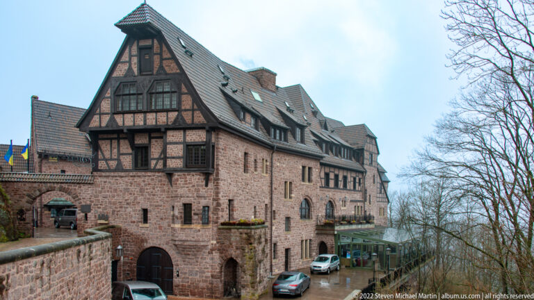 Stone and half-timbered hotel building with steep roofs beside the Wartburg approach road.