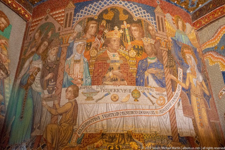 Crowned ruler seated at a table with nobles and attendants, framed by heraldic and inscription details.